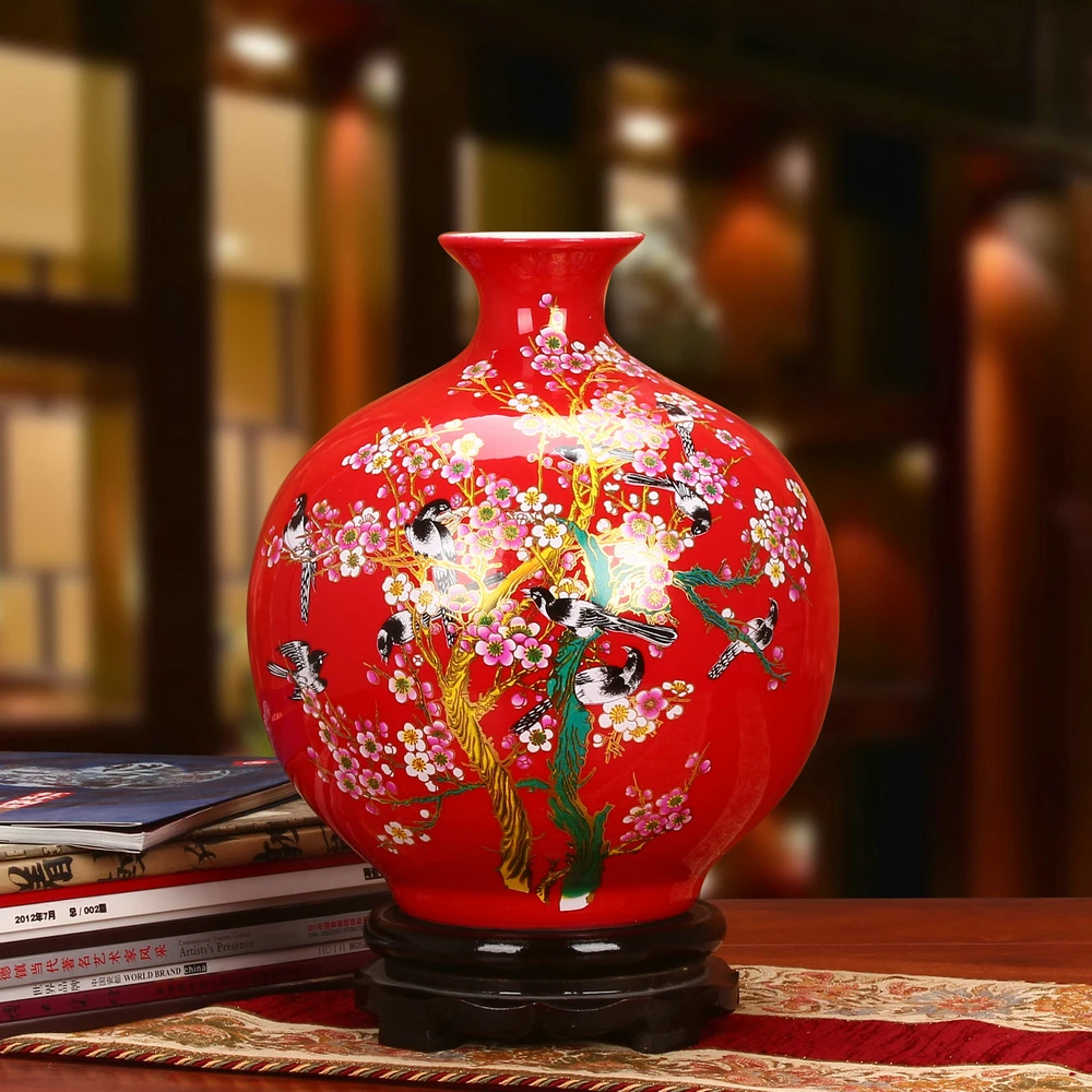 A piece of red porcelain designed with birds and flowers with splashes of color